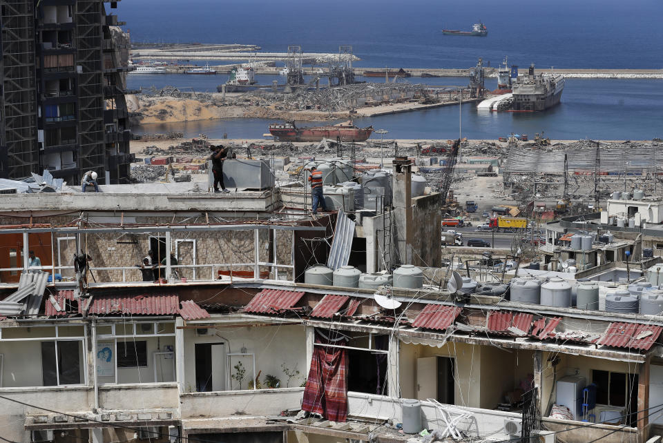 Workers repair water tanks and damaged apartments overlooking the site of the Aug. 4 explosion that hit the seaport, in Beirut, Lebanon, Thursday, Aug. 27, 2020. (AP Photo/Hussein Malla)