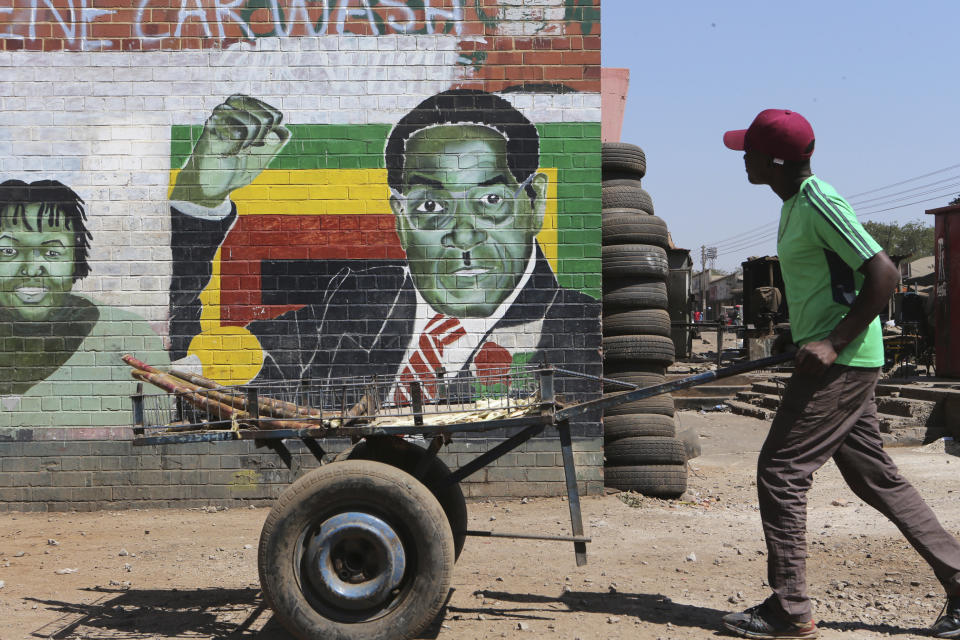 A man pushes an empty cart past a portrait of former Zimbabwean President Robert Mugabe in Harare, Friday, Sept. 6, 2019. Robert Mugabe, the former leader of Zimbabwe forced to resign in 2017 after a 37-year rule whose early promise was eroded by economic turmoil, disputed elections and human rights violations, has died. He was 95. (AP Photo/Tsvangirayi Mukwazhi)