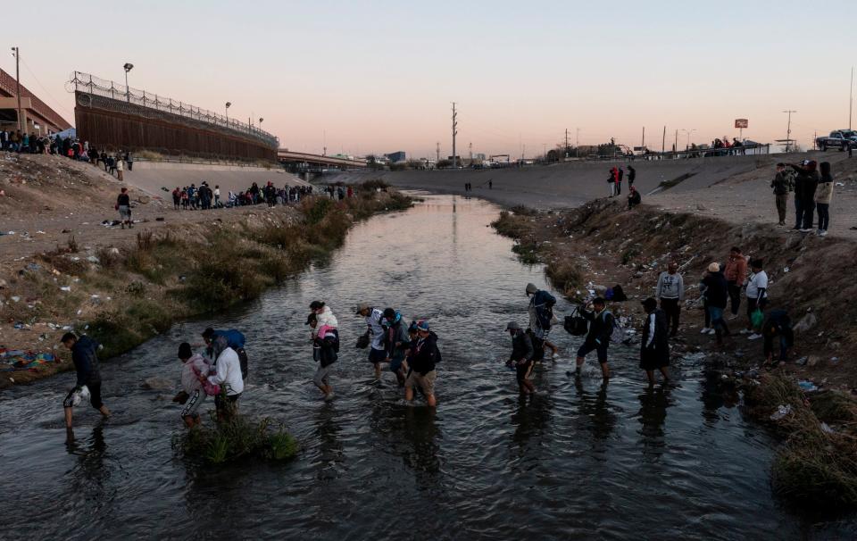 Migrants cross and line up on the north bank of the Rio Grande in El Paso, Texas on Dec. 19, 2022 after hearing that the Biden administration's plan to lift Title 42 expulsions was placed on hold by the U.S. Supreme Court.