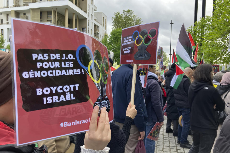 A demonstrator demanding the boycott of Israel during Olympic Games demonstrates with a poster reading "No Games for genocidal, boycott Israel" outside the Paris Olympic organizing committee headquarters, Tuesday, April 30, 2024 in Saint-Denis, outside Paris. About 300 pro-Palestinian demonstrators took part on the protest. (AP Photo/Alexander Turnbull)