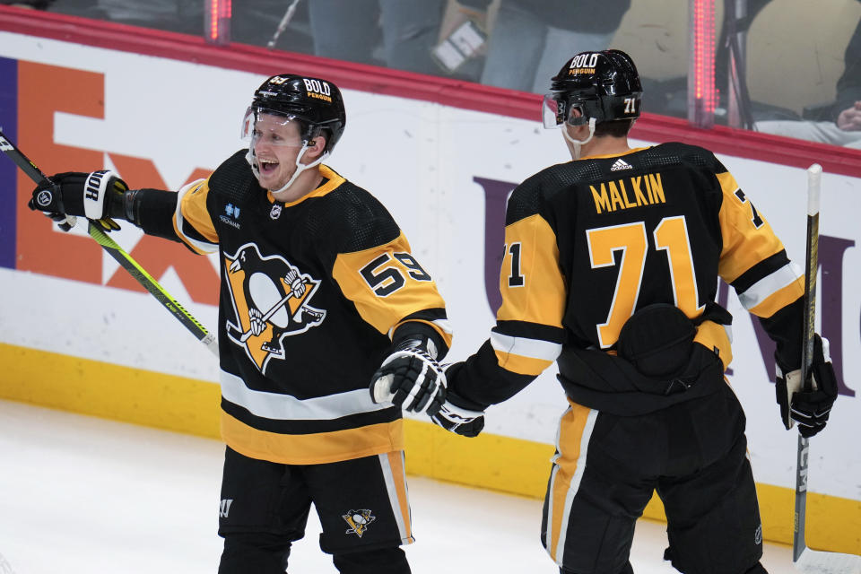 Pittsburgh Penguins' Jake Guentzel (59) celebrates his goal with Evgeni Malkin (71) during the first period of an NHL hockey game against the Arizona Coyotes in Pittsburgh, Tuesday, Dec. 12, 2023. (AP Photo/Gene J. Puskar)