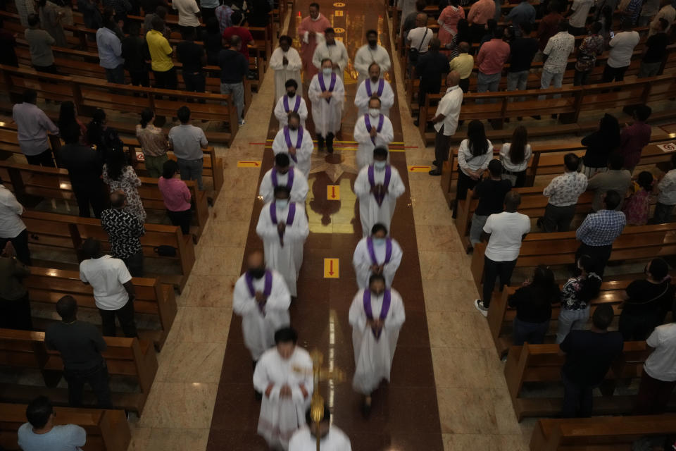 People stand as the priest leaves after a liturgy at the Catholic Church, Our Lady of the Rosary, at the Religious complex, in Doha, Qatar, Friday, Dec. 9, 2022. (AP Photo/Thanassis Stavrakis)