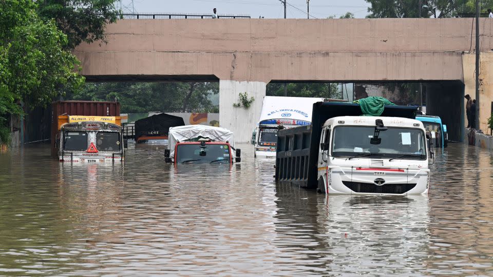 Trucks are seen partially submerged in a flooded street after the Yamuna River overflowed due to monsoon rains, in New Delhi on July 13, 2023. - Money Sharma/AFP/Getty Images