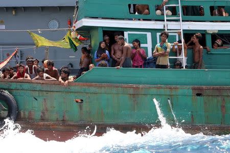 Migrants react from their boat as they are towed away from Thailand by a Thai navy vessel, in waters near Koh Lipe island May 16, 2015. REUTERS/Aubrey Belford