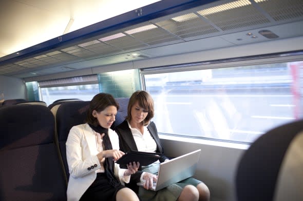 Two business women work on a train.