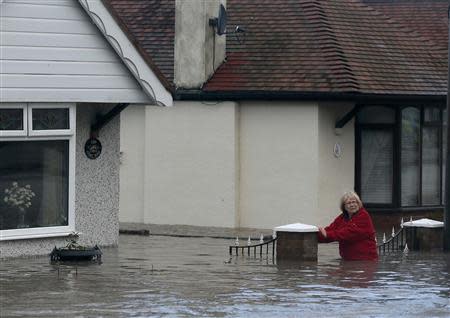 A woman stands up to her waist in flood water in a residential street in Rhyl, north Wales December 5, 2013. REUTERS/Phil Noble