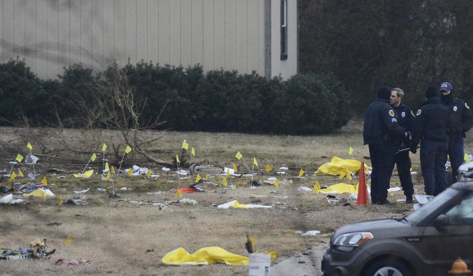 Investigators examine the site of a plane crash Tuesday, Feb. 4, 2014 near Nashville. The small plane crashed on Monday, near a YMCA in suburban Nashville, killing everyone on board and damaging cars in the parking lot. (AP Photo/Mark Zaleski)