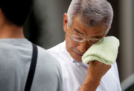 A businessman wipes his face while walking on a street during a heatwave in Tokyo, Japan July 23, 2018. REUTERS/Issei Kato