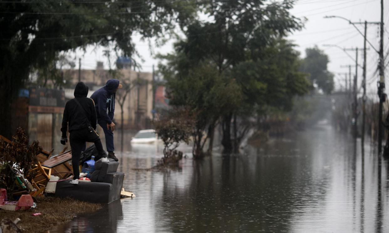 <span>Men look at a flooded street in Sarandi, one of the hardest hit by heavy rains in Porto Alegre, Rio Grande do Sul state, Brazil, on 27 May 2024.</span><span>Photograph: Anselmo Cunha/AFP/Getty Images</span>