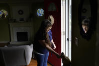 Allison Cullen, of Brockton, Mass., greets the family dog Lula, right, Thursday, July, 22, 2021, after speaking on the phone with her husband Flavio Andrade Prado, a Brazilian national, from their home in Brockton. Prado is being held by Immigration and Customs Enforcement, or ICE, at the Plymouth County House of Corrections. The number of detainees nationwide has more than doubled since the end of February, to nearly 27,000, according to recent data from U.S. Immigration and Customs Enforcement. (AP Photo/Steven Senne)