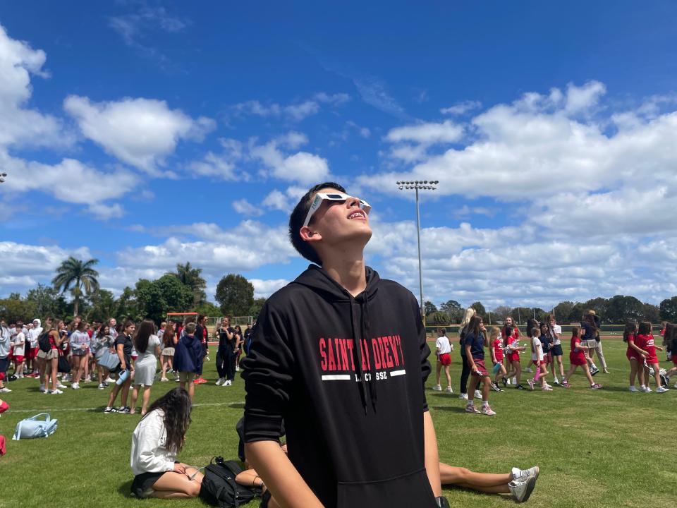 Emmanuel Bravo, 14, watches the solar eclipse on the football field at Saint Andrew's School in Boca Raton on April 8, 2024.