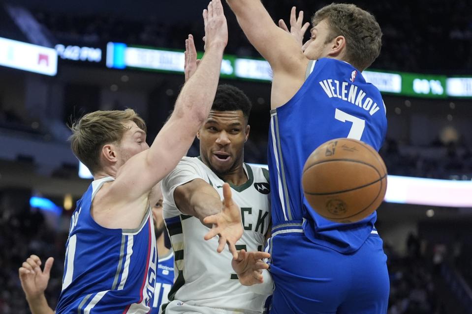 Milwaukee Bucks' Giannis Antetokounmpo p[asses between Sacramento Kings' Domantas Sabonis and Sasha Vezenkov during the second half of an NBA basketball game Sunday, Jan. 14, 2024, in Milwaukee. The Bucks won 143-142 in overtime. (AP Photo/Morry Gash)