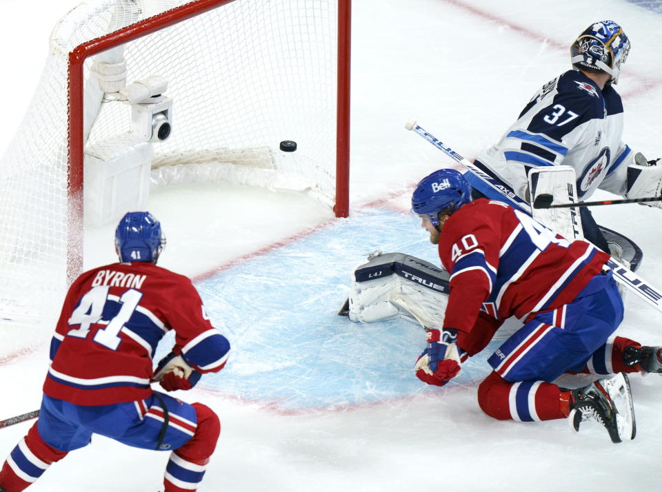 Montreal Canadiens' Joel Armia scores a short-handed goal past Winnipeg Jets goaltender Connor Hellebuyck as Canadiens' Paul Byron looks on during the second period of an NHL Stanley Cup playoff hockey game in Montreal, Sunday, June 6, 2021. (Paul Chiasson/The Canadian Press via AP)