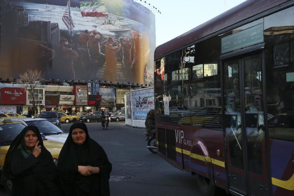 People make their way under a huge billboard showing a painting of Iranian revolutionary Guard speed boats capturing U.S. marines in the Persian Gulf, in a central square of Tehran, Iran, Monday, Jan. 30, 3017. Traditional American allies in the region have kept largely silent about President Donald Trump's executive actions to suspend issuing visas for people from several predominantly Muslim countries - Iran, Iraq, Libya, Somalia, Sudan, Syria and Yemen - for at least 30 days. Many welcome tougher action against Iran. (AP Photo/Vahid Salemi)