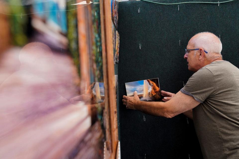 Paul James, 70, sets up his booth at the Ann Arbor Art Fair in Ann Arbor on Wednesday, July 19, 2023. The 3-day fair features almost 1,000 artists and draws in close to half a million attendees each year. James is a photographer and travels the world taking scenic landscapes to sell.