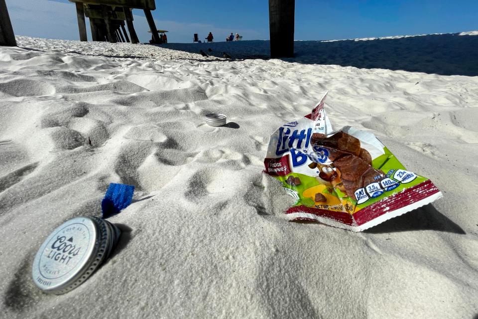 A snack food wrapper and beer bottle tops sit beneath the Okaloosa Island Fishing Pier recently. Saltwater Restaurants and the Destin-Fort Walton Beach Tourist Development Department will host beach cleanups Saturday at six locations along the coast, from Okaloosa Island east to Miramar Beach.