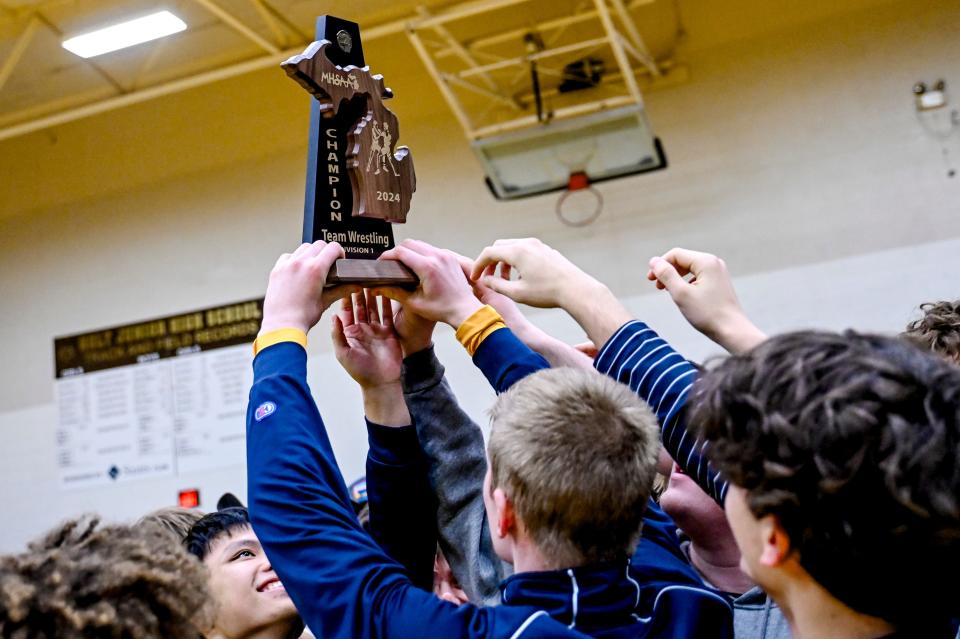 Grand Ledge wrestlers hoist the district championship trophy after beating Jackson on Wednesday, Feb. 7, 2024, at Holt Jr. High School.