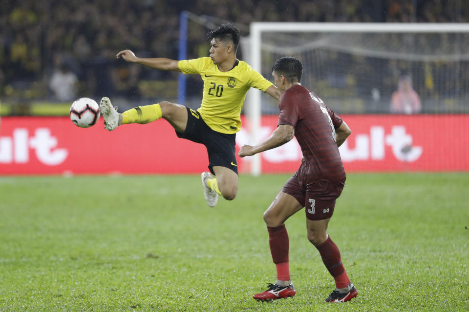 Muhammad Syafiq Ahmad of Malaysia, left, fights for the ball with Yusef Elias Dolah of Thailand during the World Cup Asia qualifying match between Malaysia and Thailand at Bukit Jail Stadium in Kuala Lumpur, Thursday, Nov. 14, 2019. (AP Photo/Vincent Thian)