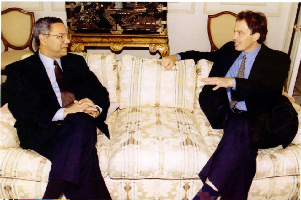 Former Labour leader Tony Blair gestures while speaking to retired US Army General Colin Powell prior to talks at a hotel in London (.)