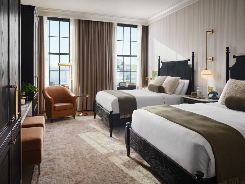 A bedroom with two queen beds, large windows, and faux leather furniture.