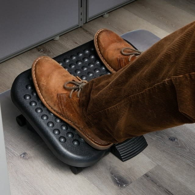 Person using a footrest under a desk, wearing brown corduroy pants and suede shoes