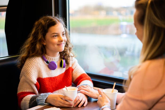 teen girl in restaurant booth looking over at a woman who is presumably her mother