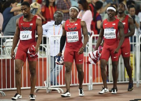 (L-R) Tyson Gay of the U.S. and his teammates Mike Rodgers, Trayvon Bromell and Justlin Gatlin walk with their national flags folded up after learning of their disqualification in the men's 4 x 100 metres relay final at the 15th IAAF Championships at the National Stadium in Beijing, China August 29, 2015. REUTERS/Dylan Martinez