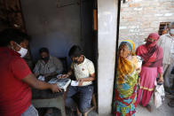 An Impoverished Indians gives his finger print on a biometric machine after purchasing food ration in Prayagraj, India, Thursday, April 2, 2020. India is adding more resources to tackle its increase in coronavirus cases by announcing that private hospitals may be requisitioned to help treat virus patients, and turning railway cars and a motor racing circuit into makeshift quarantine facilities. The steps were taken after a nationwide lockdown announced last week by Prime Minister Narendra Modi led to a mass exodus of migrant workers from cities to their villages, often on foot and without food and water, raising fears that the virus may have reached to the countryside, where health care facilities are limited. (AP Photo/Rajesh Kumar Singh)