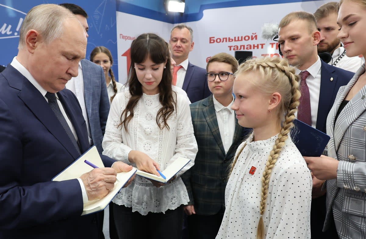 Russian president Vladimir Putin signs autographs for schoolchildren earlier this month (EPA)