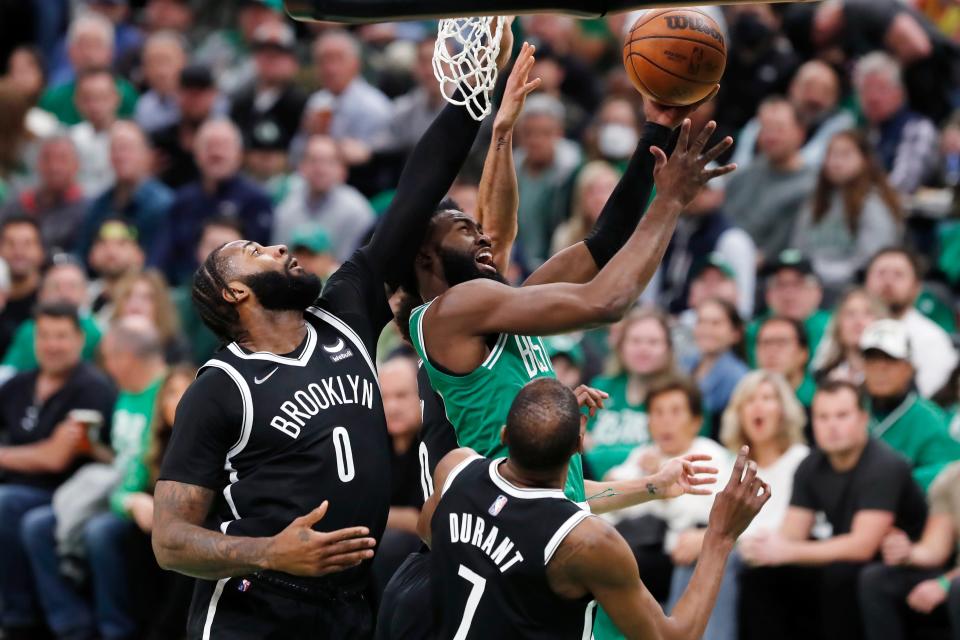 Boston Celtics' Jaylen Brown, top right, shoots against Brooklyn Nets' Andre Drummond (0) and Kevin Durant (7) during the first half of Game 2 of an NBA basketball first-round Eastern Conference playoff series Wednesday, April 20, 2022, in Boston. (AP Photo/Michael Dwyer)