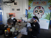 Barman Gustavo prepares drinks behind plexiglass protective wall at Maria Sol on the Santa Monica Pier as the pier restaurant opens for indoors service in Santa Monica, Calif., Wednesday, March 31, 2021. Los Angeles County can reopen even more businesses while expanding how many people are allowed to dine indoors or catch a movie, California public health officials announced Tuesday, March 30, 2021. The county of 10 million people was one of several that moved into the state's orange tier, which is the second-least restrictive of California's four-tier system. (AP Photo/Damian Dovarganes)