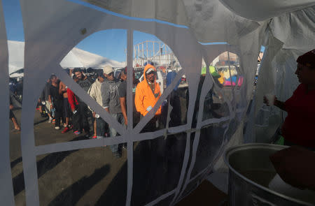 Migrants, part of a caravan of thousands from Central America trying to reach the United States, line up for a food distribution outside a temporary shelter in Tijuana, Mexico, December 7, 2018. REUTERS/Mohammed Salem