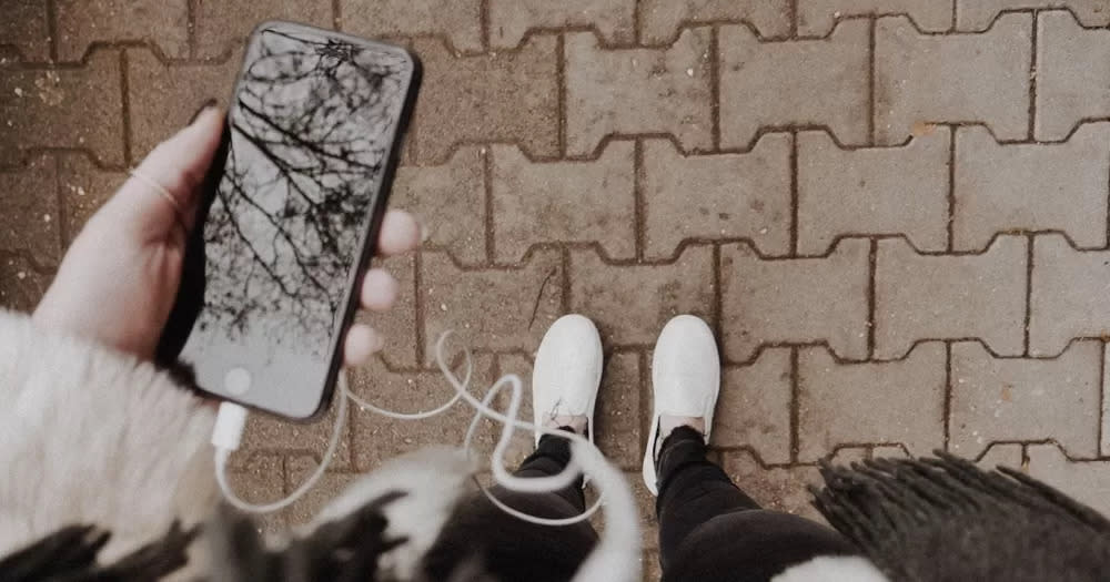 This article is about Irish podcasts. In the photo, a person holding a phone with earphones plugged in.