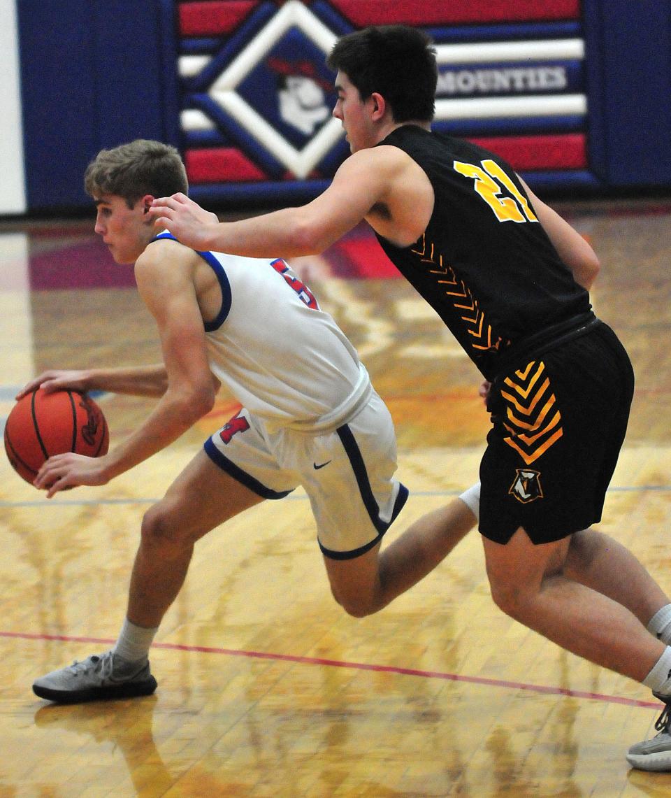 Mapleton High School’s Kyle Sloter (5) drives the ball around Monroeville High School’s Jimmy Clingman (21) during basketball action at Mapleton High School Friday, Jan. 21, 2022.