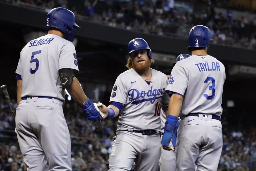 Los Angeles Dodgers' Justin Turner celebrates with Corey Seager (5) and Chris Taylor (3) after scoring runs on a double hit by Albert Pujols in the second inning of a baseball game against the Arizona Diamondbacks, Sunday, Aug 1, 2021, in Phoenix. (AP Photo/Rick Scuteri)