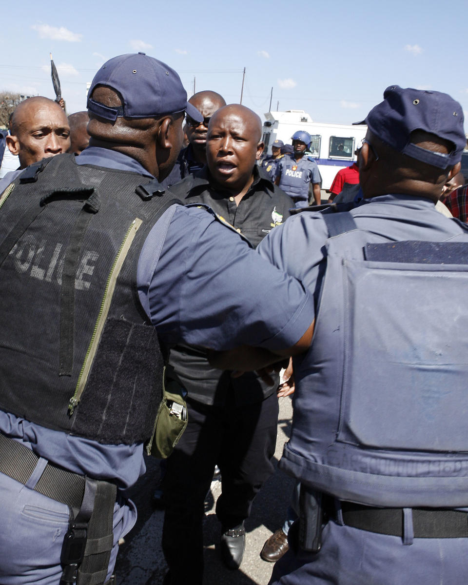 Firebrand politician Julius Malema, centre, argues with police officers, at Lonmin Platinum Mine near Rustenburg, South Africa, Monday, Sept. 17, 2012. London-registered Lonmin PLC announced it is halting construction of a new shaft, putting 1,200 people out of work, as the bloody and bitter strike at its beleaguered South African platinum mine dragged on its fifth week. The strikes that have halted work at seven gold and platinum mines have spread to the chrome sector, according to the official South African Press Association. Meanwhile, police blocked rabblerousing politician Julius Malema from addressing some 3,000 strikers gathered at a stadium at the Lonmin mine at Marikana, northwest of Johannesburg. (AP Photo/Themba Hadebe)