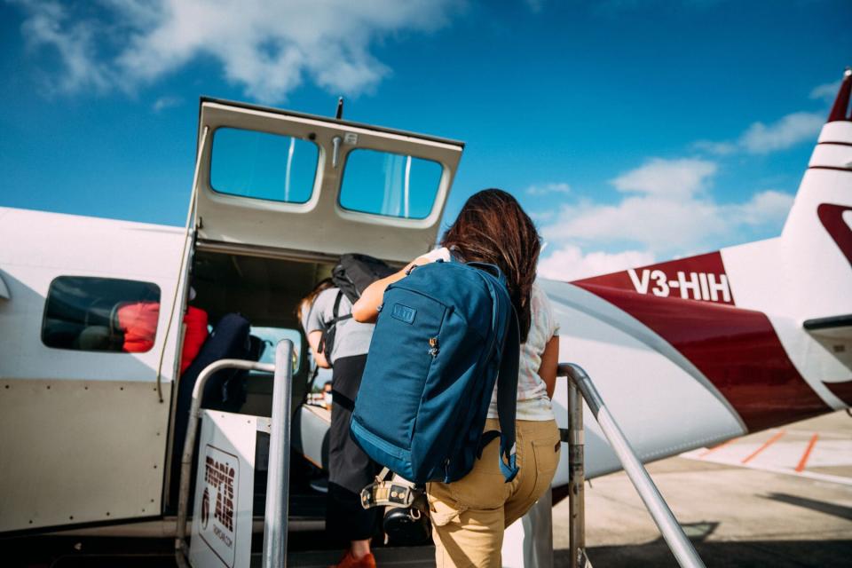 Woman holding Yeti backpack while boarding small airplane