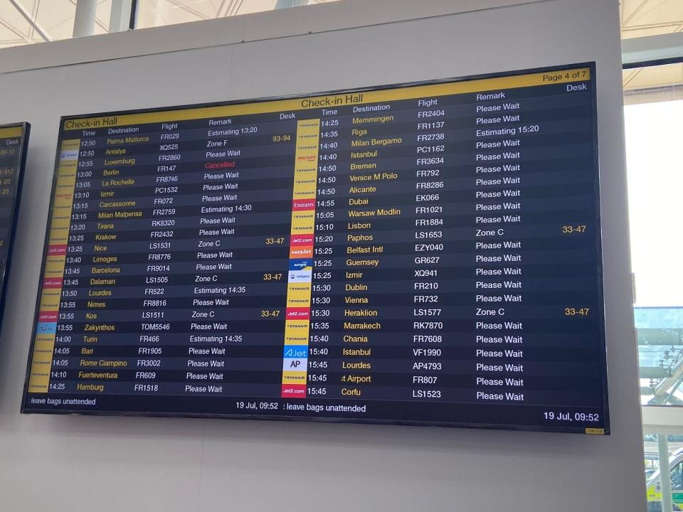 The flight Check-in Hall board at Stansted airport which shows "Please wait" signs by many flights.