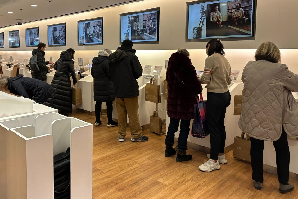 FILE - Shoppers at a Uniqlo store in New York use self-checkout on Dec. 6, 2023. Job gains and raises helped power solid economic growth in the U.S. last year, but what if those gains were a mirage? The Labor Department overestimated job gains last year by about 13%. That suggests some of Wall Street’s optimism last year was built on sand. A weaker employment market means a weaker case for consumer spending to keep propping up the economy. (AP Photo/Anne D'Innocenzio)