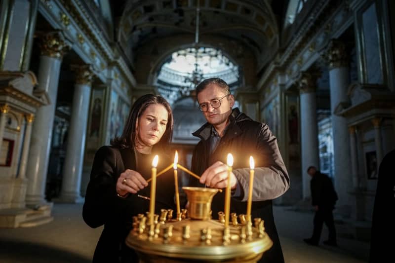 Annalena Baerbock (L), Germany's Foreign Minister, and Dmytro Kuleba, Ukraine's Foreign Minister, light a candle during a visit to the Transfiguration Cathedral in the port city of Odessa. Kay Nietfeld/dpa