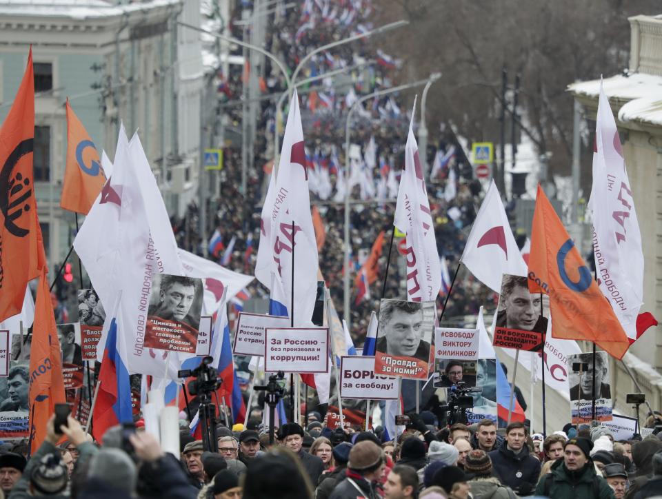 Demonstrators, with flags of different opposition movements and portraits of Boris Nemtsov, march in memory of opposition leader Boris Nemtsov in Moscow, Russia, Sunday, Feb. 24, 2019. Thousands of Russians took to the streets of downtown Moscow to mark four years since Nemtsov was gunned down outside the Kremlin. (AP Photo/Pavel Golovkin)