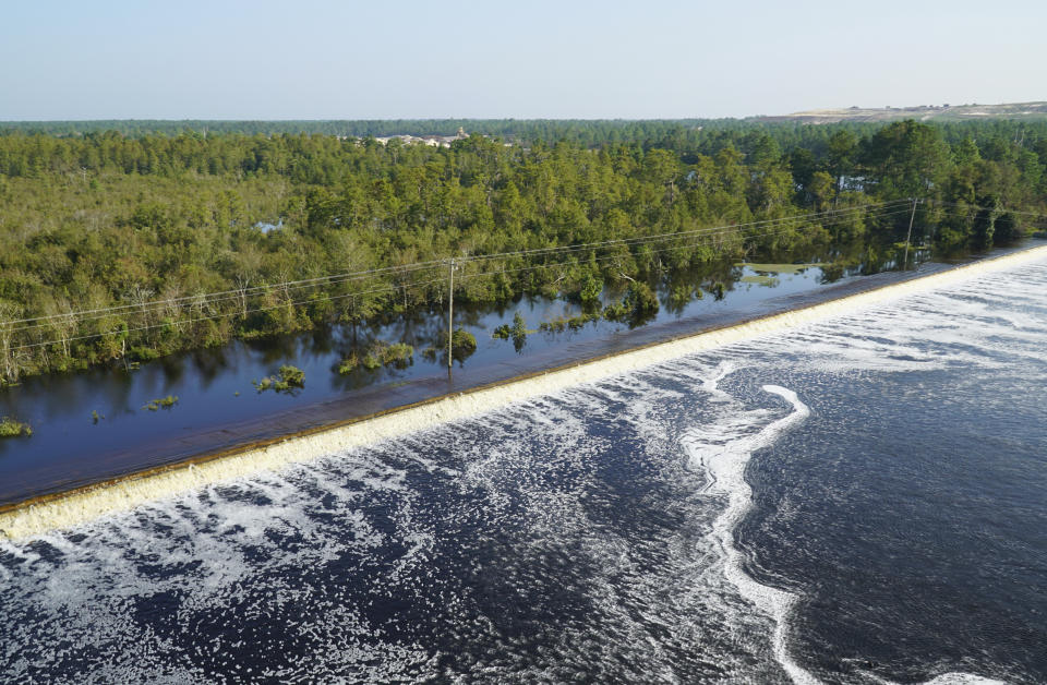 In this drone photo released by Duke Energy, flooding from the swollen Cape Fear River overtops an earthen dike at Sutton Lake, a 1,100-acre (445-hectare) lake at the L.V. Sutton Power Station near Wilmington, N.C. , Thursday, Sept. 20, 2018. Duke Energy activated a high-level emergency alert at the retired coal-fired power plant due to the flooding, raising concerns of a potential breach. (Duke Energy via AP)