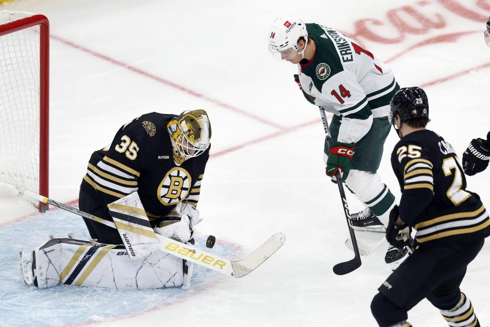 Boston Bruins' Linus Ullmark (35) blocks a shot as Minnesota Wild's Joel Eriksson Ek (14) looks for the rebound during the first period of an NHL hockey game, Tuesday, Dec. 19, 2023, in Boston. (AP Photo/Michael Dwyer)