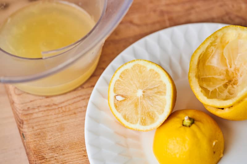 Lemons on a plate with lemon juice in a measuring cup