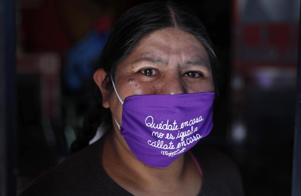 Emiliana Quispe poses for a portrait wearing a face mask that reads in Spanish: "Stay home. It's not the same as 'shut up at home,'" at the headquarters of the local feminist organization "Mujeres Creando," or Women Creating, where members are making the masks to sell amid the spread of the new coronavirus in La Paz, Bolivia, Friday, April 24, 2020. (AP Photo/Juan Karita)