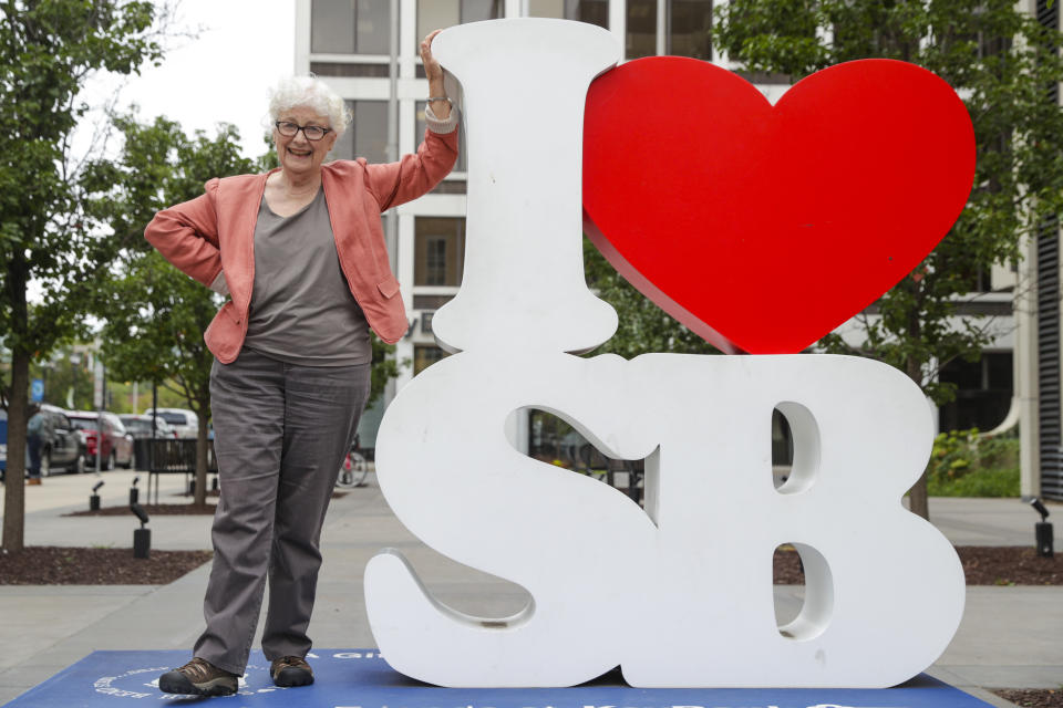 Anne Montgomery, mother of Democratic presidential candidate South Bend Mayor Pete Buttigieg, poses on an "I Love South Bend" statue outside his campaign office in South Bend, Ind., Wednesday, Sept. 25, 2019. (AP Photo/Michael Conroy)