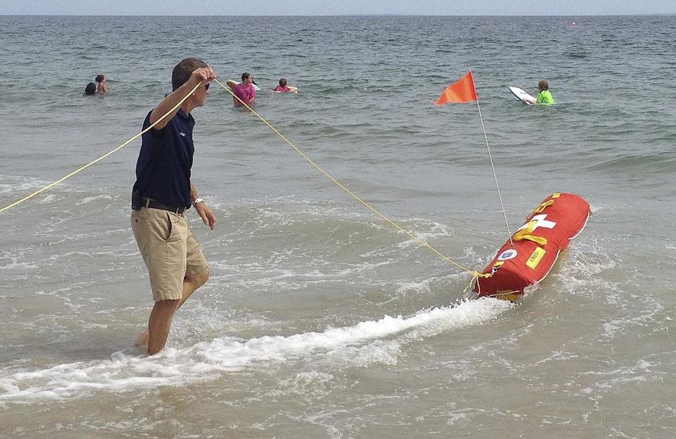 In this Wednesday, Aug, 8, 2012 photo, Misquamicut, R.I., Fire Chief Louis Misto, left, holds a line attached to the EMILY remote-control lifesaving device as it propels itself in the water and away from the shore at Old Town Beach, in Westerly, R.I. EMILY, an acronym for Emergency Integrated Lifesaving Lanyard, is a small watercraft fitted with a flotation device and can go up to 22 mph, allowing it to get to people more quickly, and in some cases more safely, than any human. (AP Photo/Michelle R. Smith)