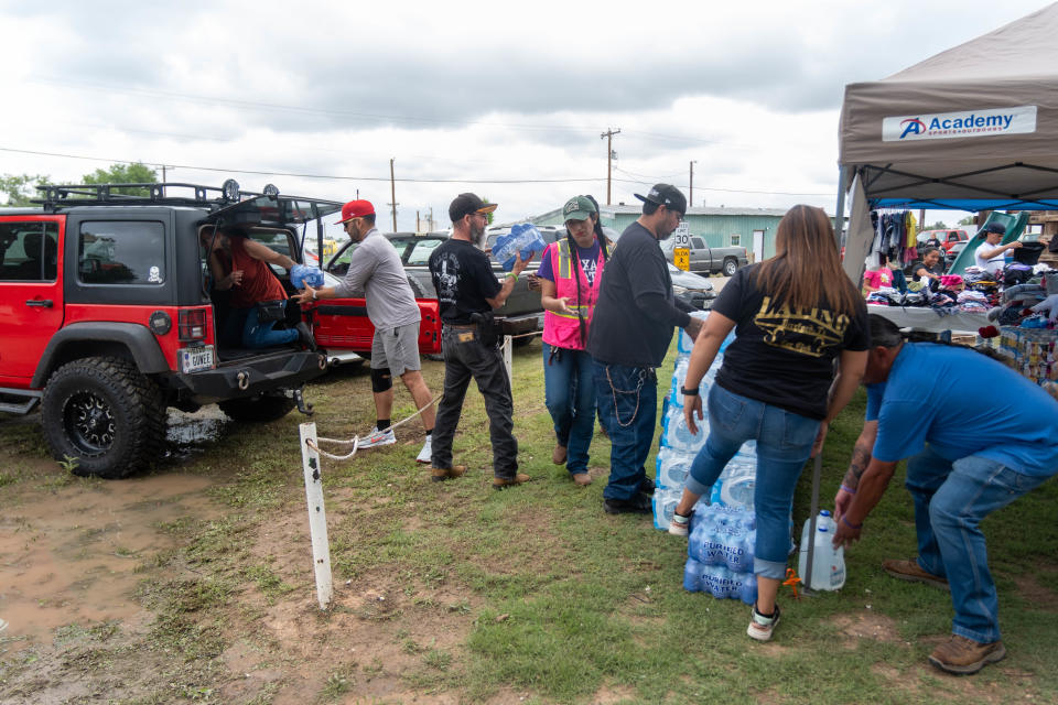 Volunteers work together to unload water in Hereford Texas Sunday at a local park to help flooded residents.