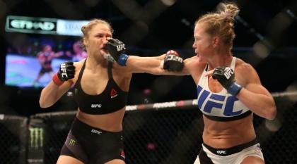 Rousey takes a punch from Holm. (UPROXX)