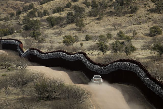 <p>AP Photo/Charlie Riedel</p> A razor wire–covered border wall along the Arizona-Mexico border in 2019